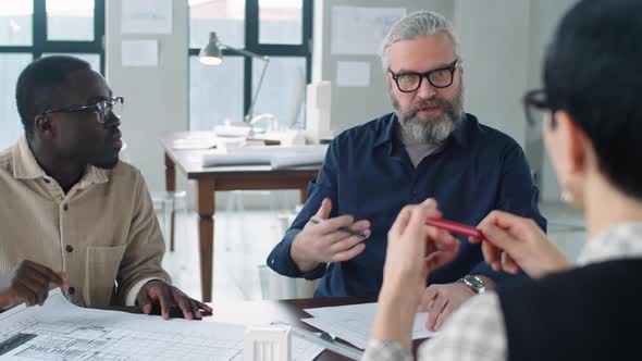 Diverse Mixed Age Male Architects Speaking with Female Colleague at Meeting alt