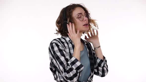 Attractive Young Girl in Plaid Shirt Dancing and Singing with Big Headphones Music and Feel Good alt