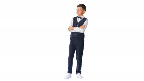 Little Boy in a Bow Tie Standing with Crossed Arms and Looking Up on White Background