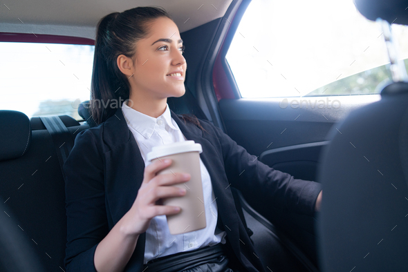 Business woman drinking coffee in car.