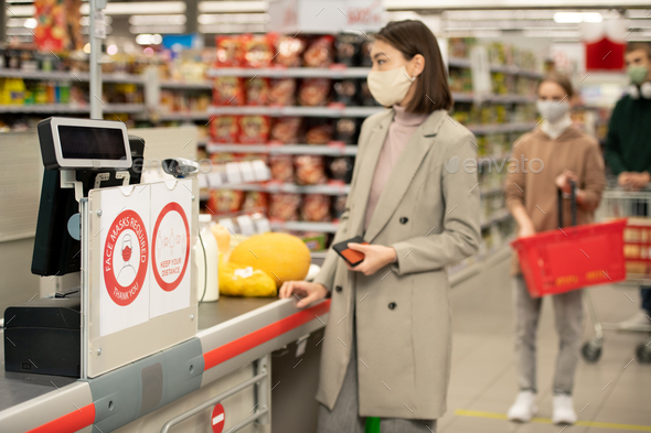 Board on checkout counter announcing requirement about wearing protective masks