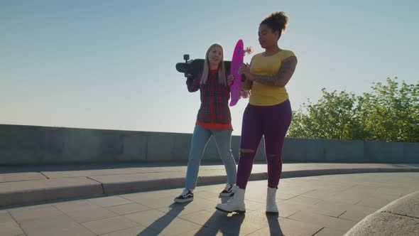 Cool Pretty Female Skateboarders with Skateboards Walking at Dawn alt