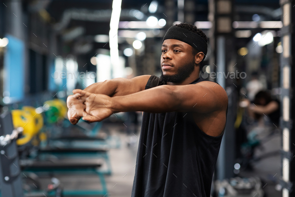 Athletic millennial black man warming up and stretching Stock