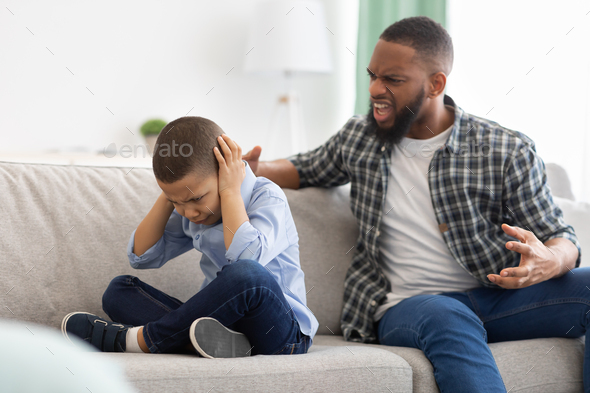 Angry African Father Shouting At Scared Son Sitting At Home
