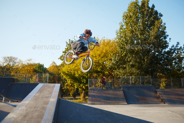 Bmx biker rides by railing in skatepark