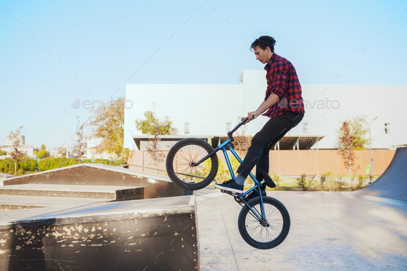Young bmx biker doing trick, training in skatepark