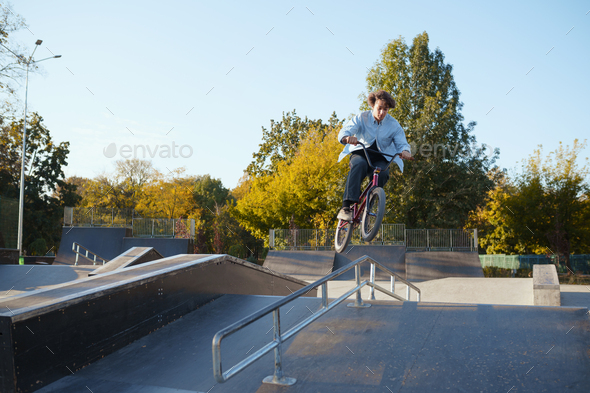 Bmx biker rides by railing in skatepark