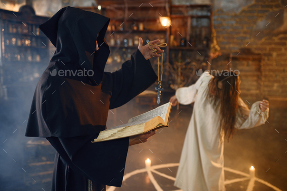 Exorcist in hood casting out demons from a woman