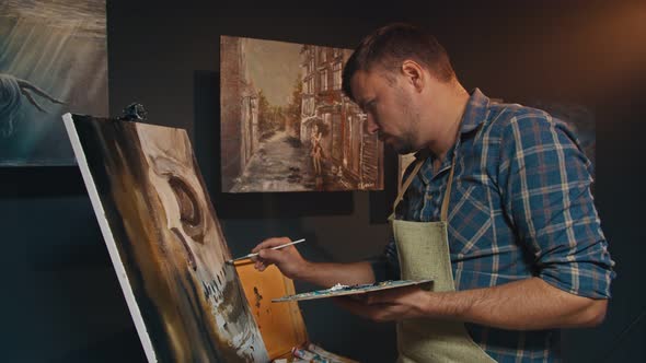 The Artist Paints a Picture with Oil Paints in His Studio alt
