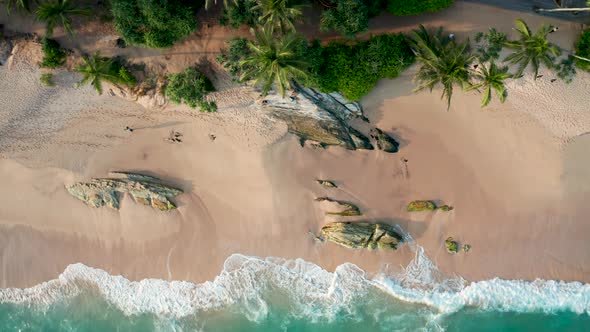 Ocean Waves Crash Against Stony Rocks During Sunset on the Island of Sri Lanka. Aerial View