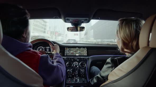 The driver behind the wheel of the car points to the passenger on the road.