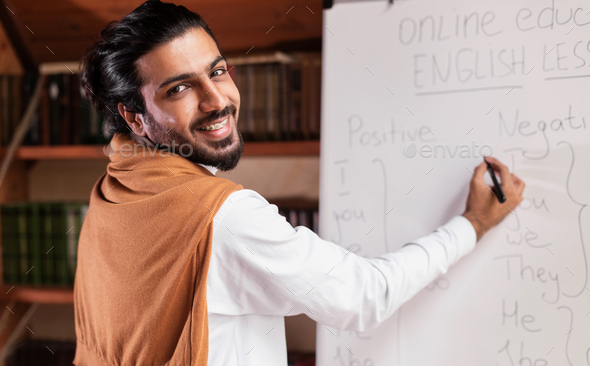 Arab Teacher Writing On Blackboard Having Online Lecture Indoor