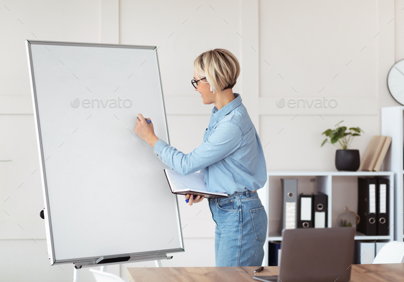 Online tutoring concept. Young female teacher writing on empty blackboard during web lesson, space
