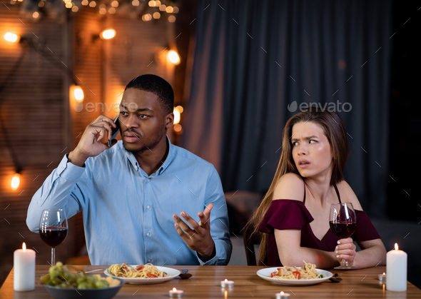 Black Guy Talking On Cellphone At Date While His Girlfriend Sitting Boring