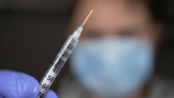 Doctor in Blue Gloves Offers Syringe with Vaccine