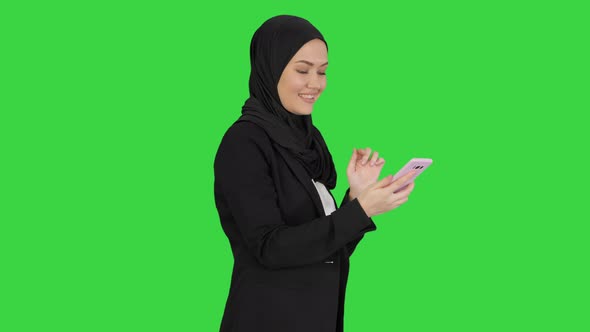 Muslim Girl in Hijab Using Smartphone To Send Voice Messages on a Green Screen, Chroma Key. alt