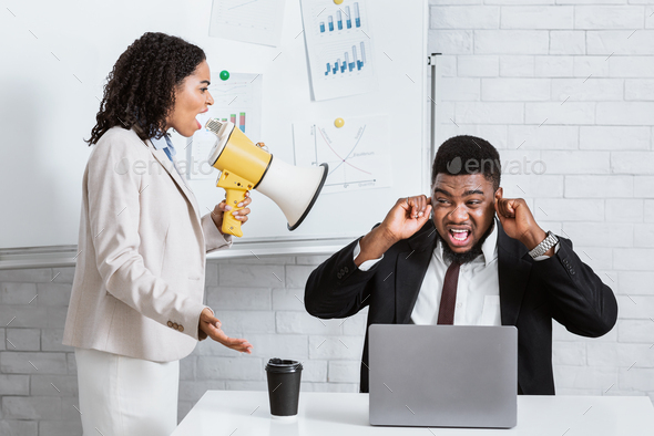 Enraged female boss with loudspeaker screaming at her scared subordinate at  company office Stock Photo by Prostock-studio