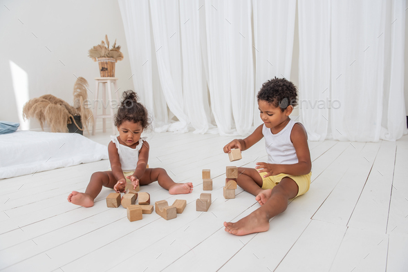 Little Brother and Sister African American play houses with wooden eco bricks build destroy towers