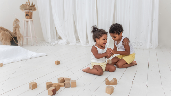 Little Brother and Sister African American play houses with wooden eco bricks build destroy towers