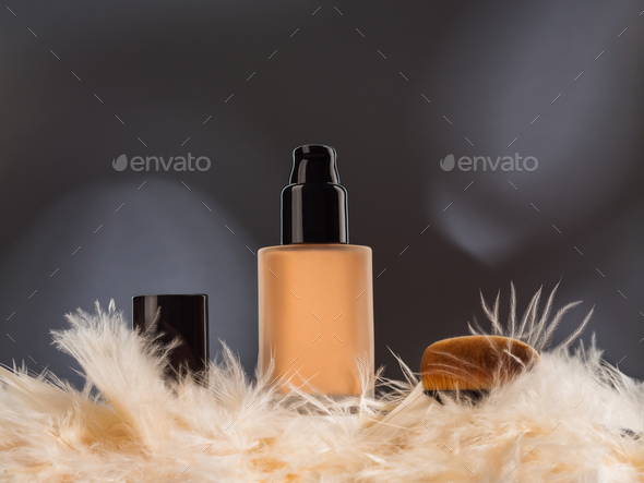 Unbranded generic foundation bottle with feathers and brush on gray background
