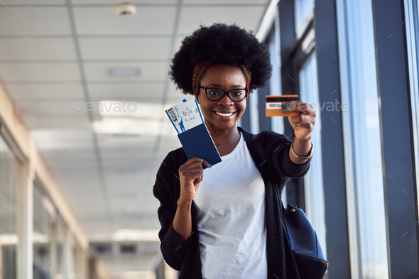 Young african american female passanger in casual clothes is in airport holding tickets