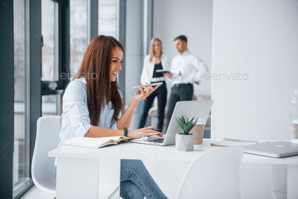 Woman with laptop sitting in front of group of young successful team