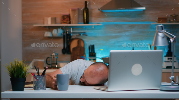 Overworked man sleeping on kitchen desk