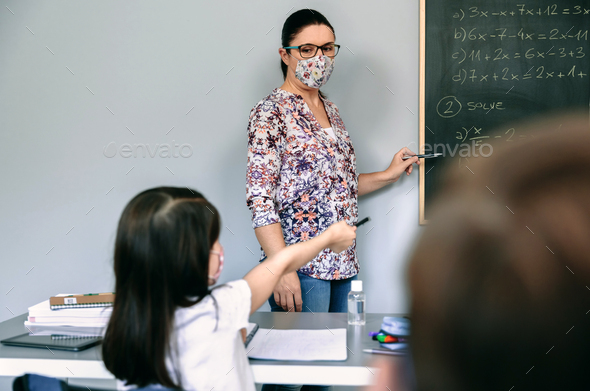 Teacher with mask explaining exercises in math class