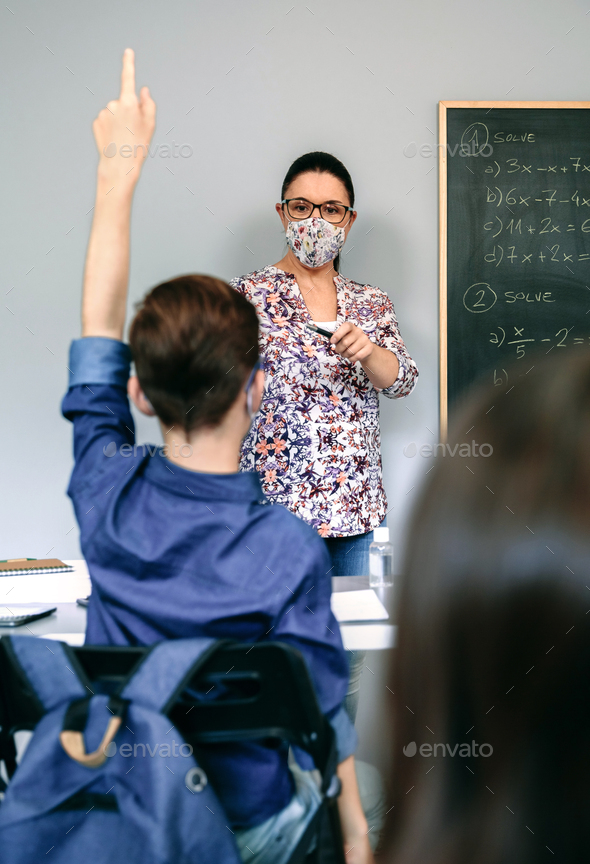 Teacher with mask in math class with student raising hand