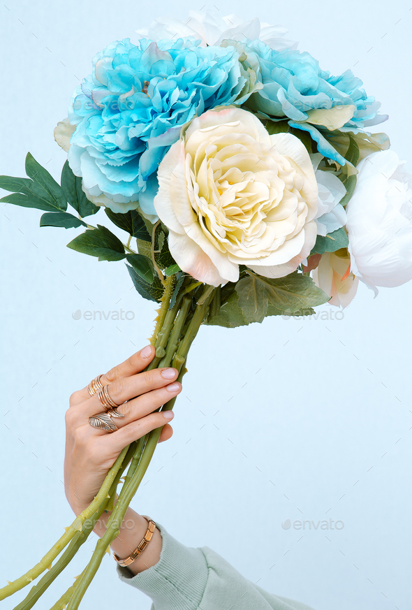 Female hand holding bouquet of spring flowers. Minimalist aesthetic fashion concept