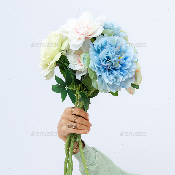 Female hand holding bouquet spring flowers. Minimalist fashion decor concept