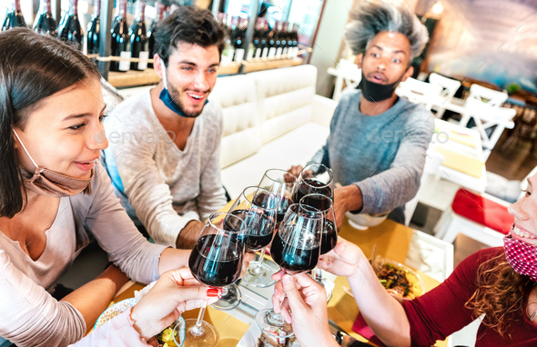 People toasting wine at restaurant wearing face masks