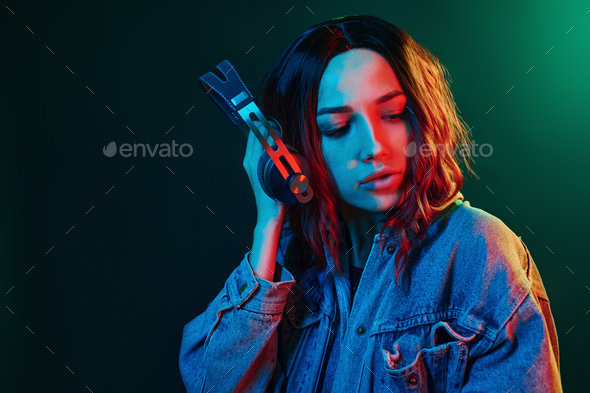 Portrait of young girl that listening to music in headphones in red and blue neon in studio
