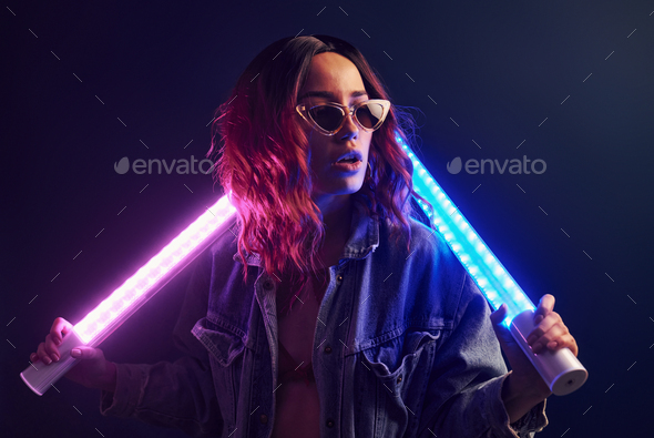 Portrait of young girl in glasses holding light sticks in red and blue neon  in studio Stock Photo by mstandret