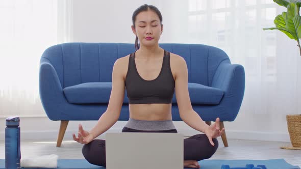 Athlete Asian indian woman looking laptop practice yoga lotus pose online course at home alt