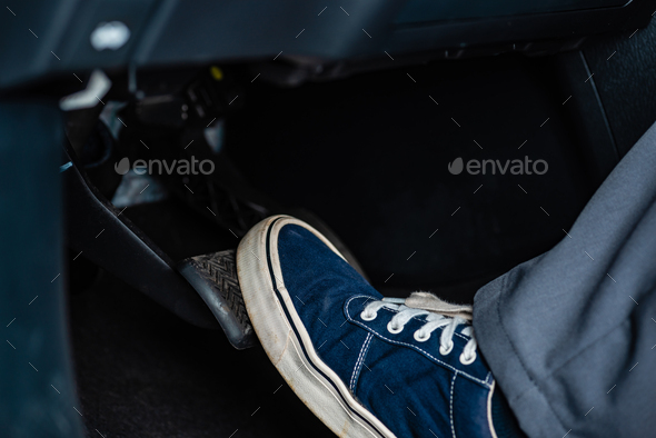 partial view of mechanic in sneakers pressing brake pedal in car