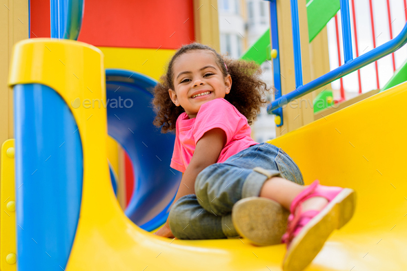 Cute little african american boy sliding down the slide, kid