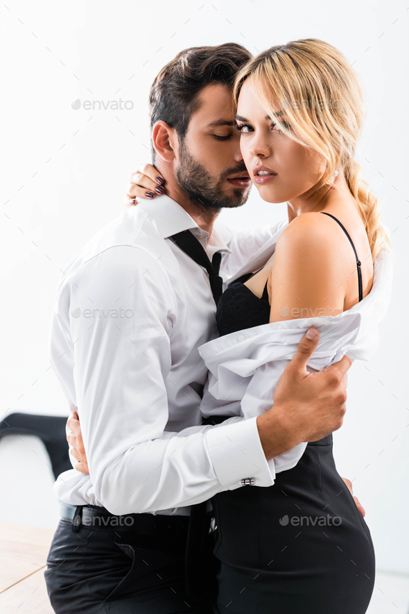 Businessman hugging seductive colleague on office table