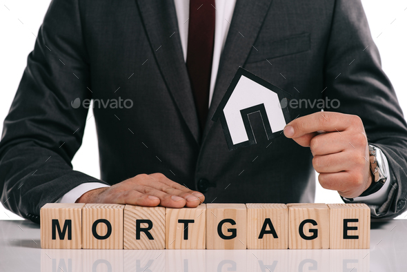 cropped view of mortgage broker holding paper house near wooden blocks isolated on white