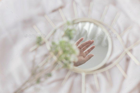 Hand reflected in mirror on background of soft fabric with manuka flowers, aesthetics. Mental Health