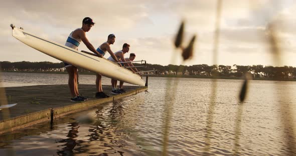 Male rower team taking out of the lake the boat alt