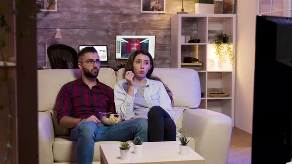 Couple Sitting on Couch and Eating Chips While Watching a Movie alt