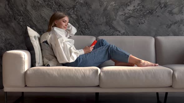 Young Woman Using Smartphone on a Sofa