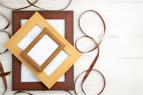 Above view of empty wooden picture frames in different sizes around ribbon on white background