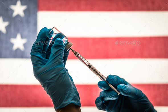 Front Line Worker Holding Syringe and Vial Filled with Coronavirus Vaccine Against American Flag