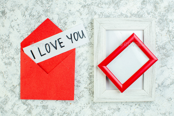 top view i love you written on paper in red envelope red and white picture frames on grey table