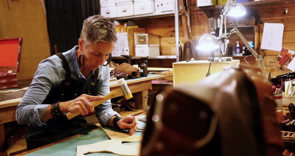 Attentive craftswoman nailing leather alt