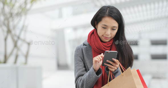 Woman use of smart phone and holding shopping bag - Stock Photo - Images