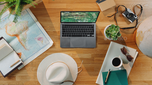 Flat lay top view desktop travel concept with laptop, maps and other travel essentials.