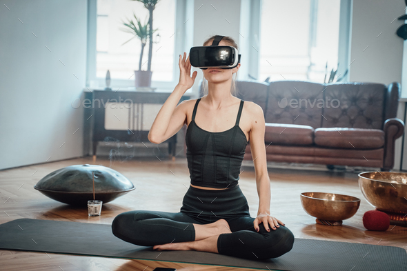 Woman weared with virtual reality headset does yoga at home Stock Photo by  fxquadro